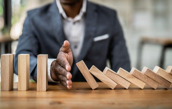 businessman-halts-falling-domino-with-hand-symbolic-control-preventing-chain-reaction